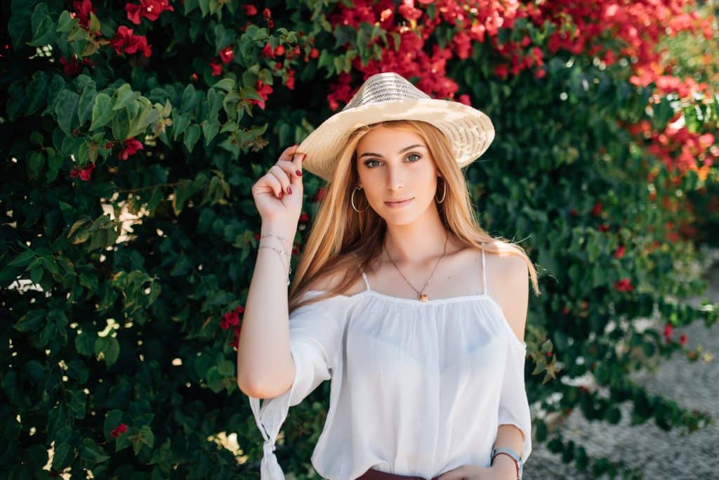 outdoor close up portrait young beautiful happy smiling curly girl wearing stylish straw hat street near blooming roses summer fashion concept copy space